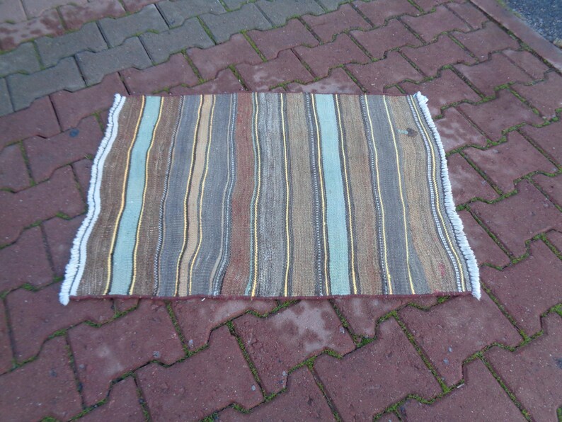 May include: A striped rug with a white fringe. The rug has stripes of brown, blue, yellow, and gray.