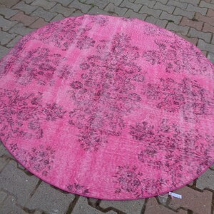 May include: A round pink rug with a faded floral pattern in a darker shade of pink.