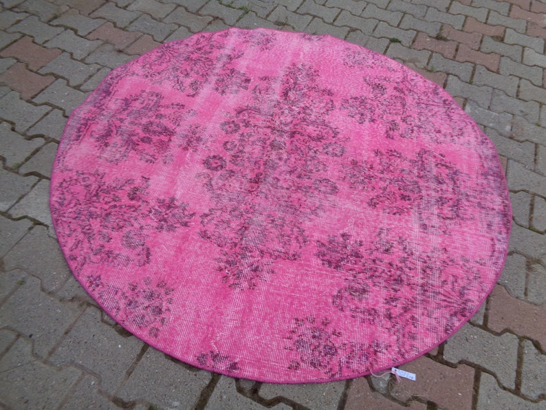 May include: A round pink rug with a faded floral pattern in a darker shade of pink.