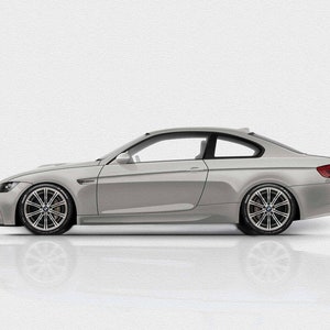 May include: A silver grey coupe car with black tinted windows and black rims. The car is parked on a white surface.