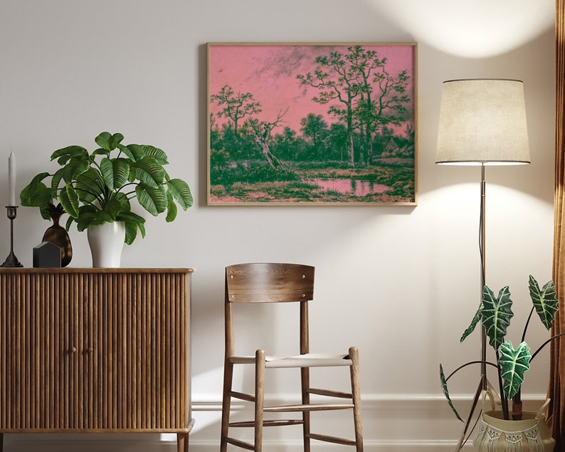 Puede incluir: Una pintura de paisaje enmarcada con un cielo rosa y &aacute;rboles verdes reflejados en un cuerpo de agua tranquilo. La pintura est&aacute; colgada en una pared blanca sobre un gabinete de madera.