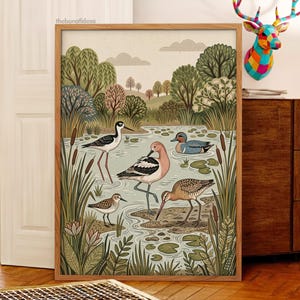 Puede incluir: Una l&aacute;mina de arte enmarcada que presenta una ilustraci&oacute;n detallada de un humedal con cuatro especies de aves distintas, incluyendo una cig&uuml;e&ntilde;uela, una avoceta, un correlimos peque&ntilde;o y un pato azul entre juncos y nen&uacute;fares.