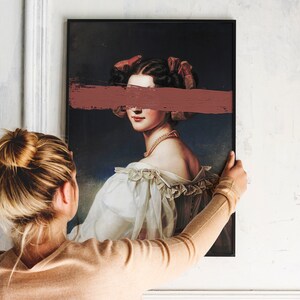 May include: A framed portrait of a woman with a pink ribbon in her hair. A horizontal pink brushstroke covers her eyes. The woman is wearing a white dress with lace trim.