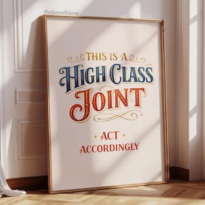 Peut inclure: Affiche encadrée avec le texte "THIS IS A HIGH CLASS JOINT ACT ACCORDINGLY". Le texte est de style vintage avec des lettres bleues et rouges et des accents dorés. L'affiche est appuyée contre un mur blanc.