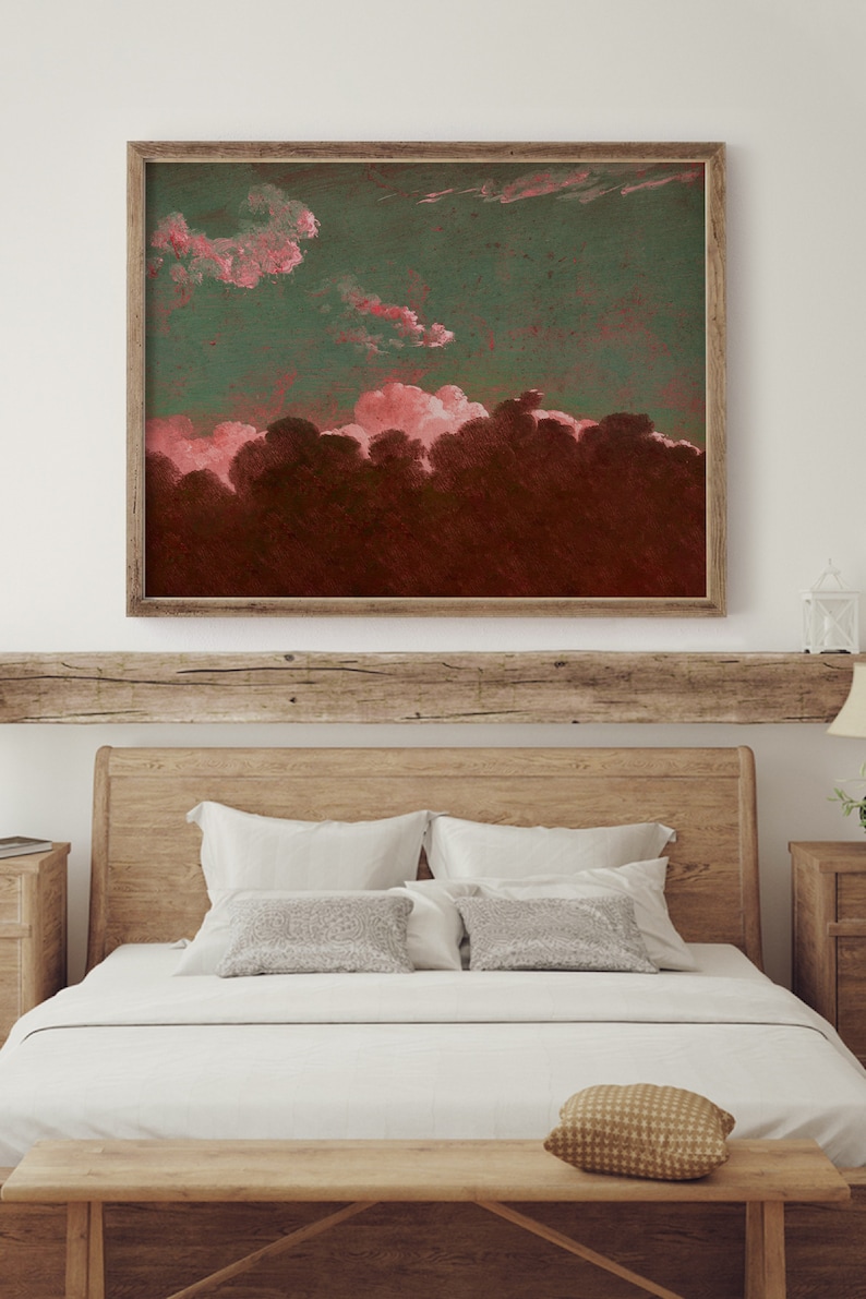 May include: A framed painting of a pink and green sunset over a dark forest. The painting is hanging on a white wall above a wooden bed with white bedding and pillows.