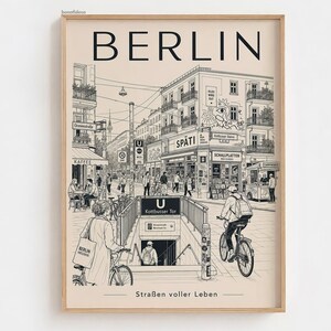 Puede incluir: Una lámina de arte enmarcada con un dibujo lineal detallado en blanco y negro de una escena callejera de Berlín. El texto BERLIN aparece en la parte superior y Straßen voller Leben en la inferior. Muestra una entrada de metro, ciclistas y edificios.