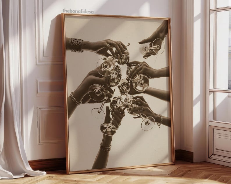May include: Sepia-toned framed print featuring multiple hands holding champagne glasses in a celebratory toast. The artwork has a vintage aesthetic, with the hands adorned with jewelry. The print is displayed against a neutral wall, adding to its classic appeal.