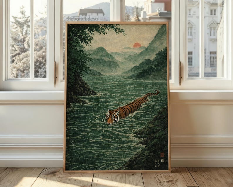 May include: A framed print depicting a tiger swimming in a river, set against a backdrop of mountains and a red sun. The artwork features a tiger with orange and black stripes, with green water and mountains in the background.