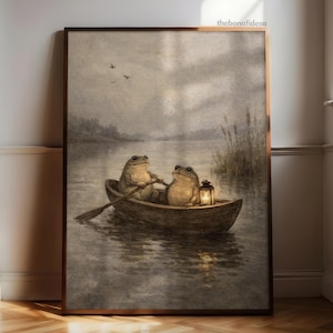Könnte beinhalten: Ein gerahmter Kunstdruck zeigt zwei anthropomorphe Frösche in einem Ruderboot auf einem See. Ein Frosch rudert, während der andere eine Laterne hält. Das Kunstwerk hat einen Vintage- und skurrilen Stil mit gedämpften Farben und einer ruhigen Atmosphäre.