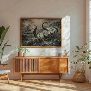 May include: A framed black and white nautical art print depicts a ship battling a giant sea creature. The artwork is displayed above a wooden cabinet with a mid-century modern design. The room is decorated with plants and a wooden chair.