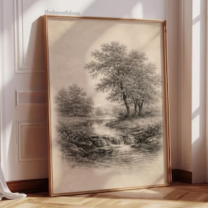 Op de afbeelding: Een ingelijste landschapskunstafdruk met een serene rivierlandschap met bomen en een kleine waterval. Het kunstwerk is in zwart-wit, met een sepia-getinte achtergrond, en wordt weergegeven in een goudkleurige lijst. Thebonafidesa staat linksboven afgedrukt.