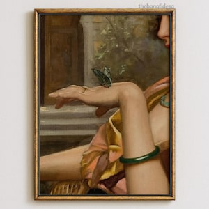 May include: A framed painting depicts a person's arm and hand with a butterfly perched on the fingers. The person wears a green bracelet and a ring. The painting has a gold frame and a classical style.