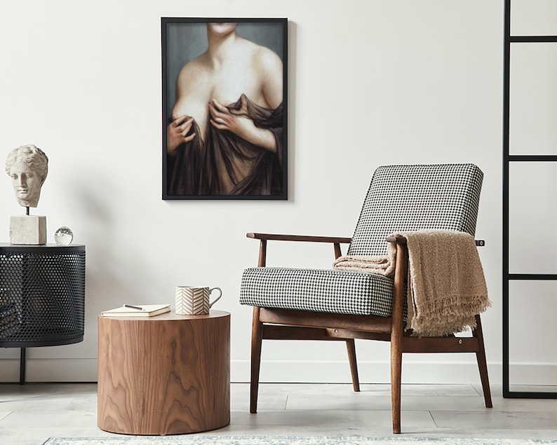 May include: A black and white checked armchair with a wooden frame and a beige throw blanket. The chair is in a living room setting with a wooden side table and a framed painting of a woman on the wall.