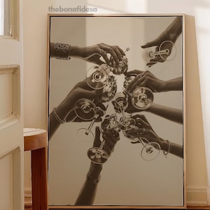 May include: Monochrome print of hands holding wine glasses in a celebratory toast. The image is framed in a light wood frame. The bonafidesa text is in the upper left corner.