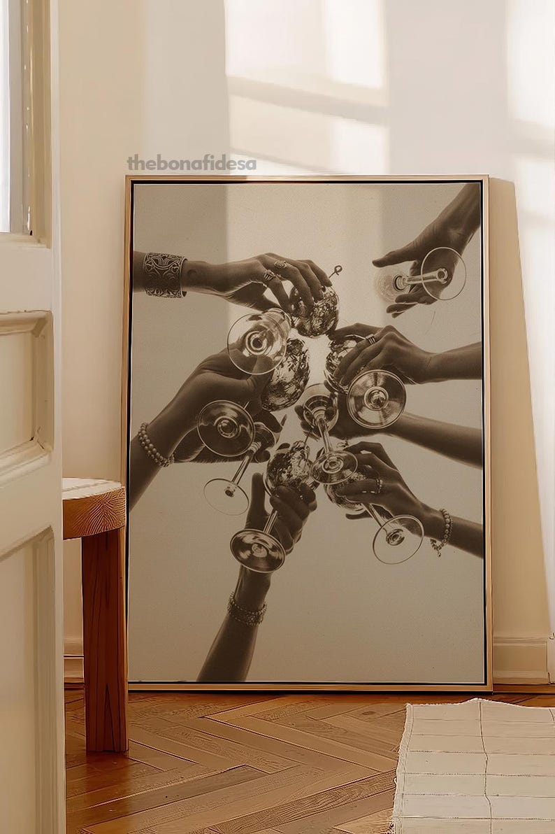 May include: Monochrome print of hands holding wine glasses in a celebratory toast. The image is framed in a light wood frame. The bonafidesa text is in the upper left corner.