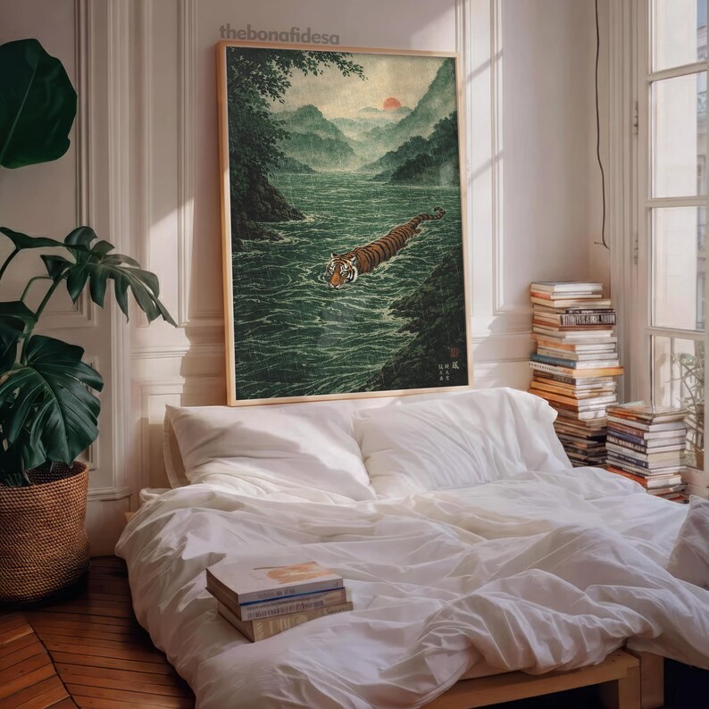 May include: A framed art print shows a tiger swimming in a river, with mountains and a sunset. The artwork is in a traditional Japanese style, with a natural colour palette. The print is displayed above a bed.