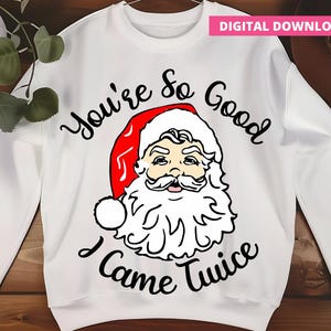 May include: White sweatshirt with a Santa Claus graphic. The Santa illustration features a red hat, white beard, and a smiling face. The text "You're so Good I Came Twice" is printed in black script.