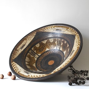 May include: A large, decorative ceramic bowl with a dark brown exterior and intricate interior patterns in shades of brown, tan, and cream. The bowl features geometric and stylized wheat designs.