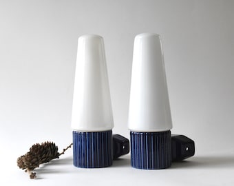 Puede incluir: Par de lámparas de cerámica blanca en forma de cono con bases de rayas azules y blancas. Las lámparas tienen un diseño simple y moderno.