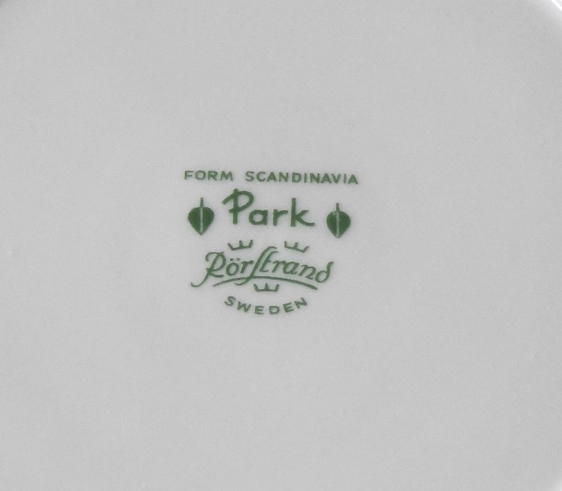 Puede incluir: Plato de cer&aacute;mica blanca con texto y logotipo verdes. El texto dice "FORM SCANDINAVIA Park R&ouml;rstrand SWEDEN". El logotipo presenta un dise&ntilde;o de hoja. El plato probablemente forma parte de un juego de vajilla.