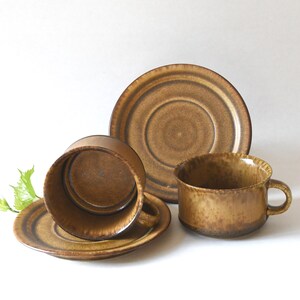 May include: A set of two brown ceramic coffee cups and saucers. The cups and saucers have a mottled brown glaze.