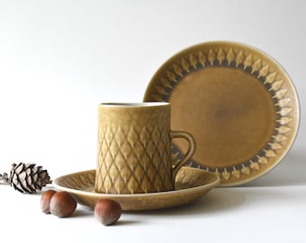 May include: A set of brown ceramic coffee cup and saucer with a leaf pattern. The cup and saucer have a textured surface.