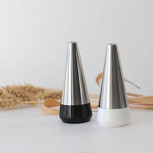 Puede incluir: Dos saleros y pimenteros de acero inoxidable con base negra y blanca.