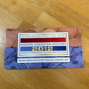 May include: A commemorative coin and currency set from 2012, featuring the text "Making American History." The set includes the text "United States Mint 220 Years" and "Bureau of Engraving and Printing 150 Years."