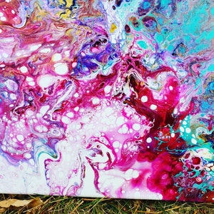 May include: Abstract painting with swirling patterns of pink, white, blue, and gold. The paint has a fluid, almost liquid appearance, creating a sense of movement and energy.