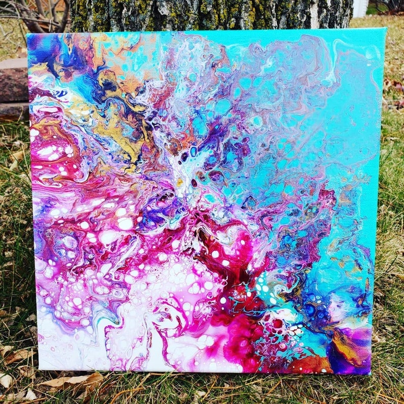 May include: Abstract painting on canvas with swirling colors of blue, pink, white, and gold. The colors blend together to create a unique and eye-catching design.