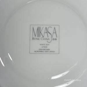 K&ouml;nnte beinhalten: Wei&szlig;e Mikasa Bone China Untertasse mit den Worten "White Silk A7050 Dishwasher Microwave Safe - Japan" auf der Unterseite.