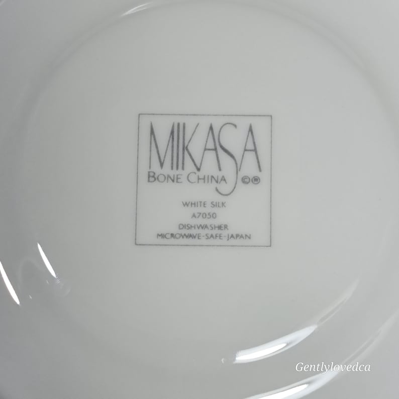 K&ouml;nnte beinhalten: Wei&szlig;e Mikasa Bone China Untertasse mit den Worten "White Silk A7050 Dishwasher Microwave Safe - Japan" auf der Unterseite.