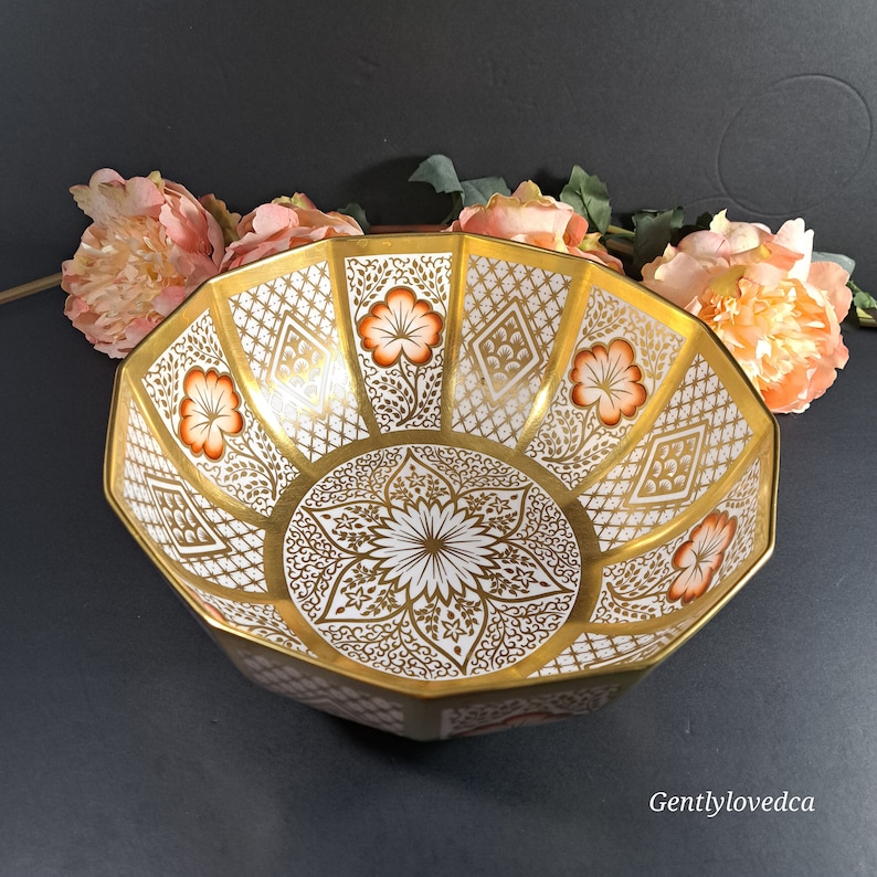 May include: A large, white porcelain bowl with a gold and orange floral design. The bowl has a scalloped edge and is decorated with intricate patterns.