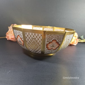 May include: A large, octagonal, white porcelain bowl with a gold rim and intricate floral and geometric patterns in gold and orange.