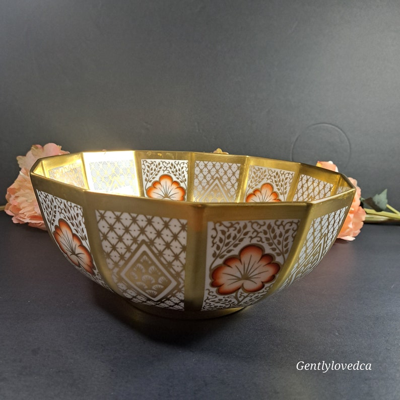 May include: Octagonal porcelain bowl with a gold rim and intricate floral designs in shades of orange and brown on a white background.