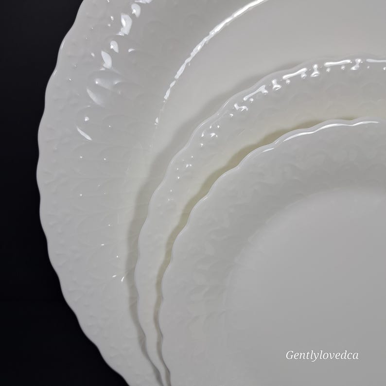 K&ouml;nnte beinhalten: Set aus drei wei&szlig;en Keramik-Dinnertellern mit einem erhabenen, strukturierten Design. Die Teller sind &uuml;bereinander gestapelt, wobei der gr&ouml;&szlig;te Teller unten und der kleinste Teller oben liegt.