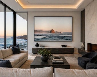 May include: A modern living room with a large framed landscape painting above a low cabinet. Beige sofas with dark blue pillows face a dark square coffee table. A fireplace with a lit fire is on the right.
