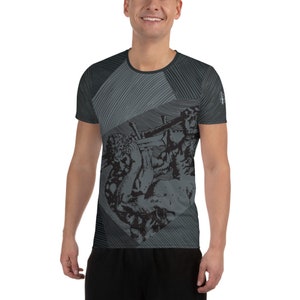 May include: A black and gray short-sleeved shirt with a geometric pattern and a graphic print of two figures wrestling. The shirt has a crew neck and a relaxed fit.