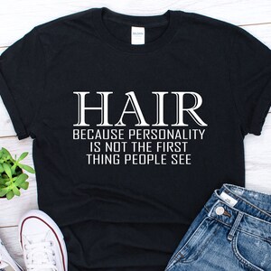 May include: Black t-shirt with white text that reads "HAIR because personality is not the first thing people see".