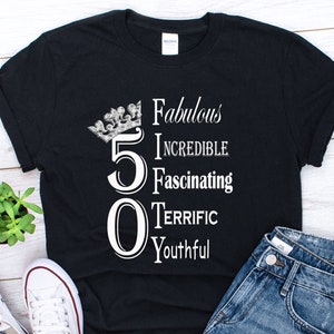 May include: Black t-shirt with a white crown and the number 50. The text "Fabulous, Incredible, Fascinating, Terrific, Youthful" is written vertically next to the number.