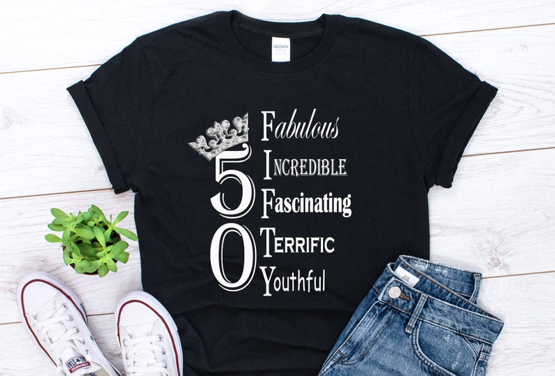 May include: Black t-shirt with a white crown and the number 50. The text "Fabulous, Incredible, Fascinating, Terrific, Youthful" is written vertically next to the number.