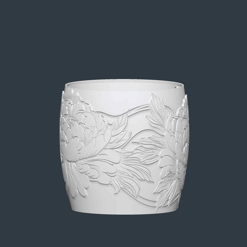 May include: A white cylindrical vase with a detailed floral relief pattern. The design features large peony blossoms and leaves, creating a textured surface. The vase has a smooth, unadorned rim and a dark background.