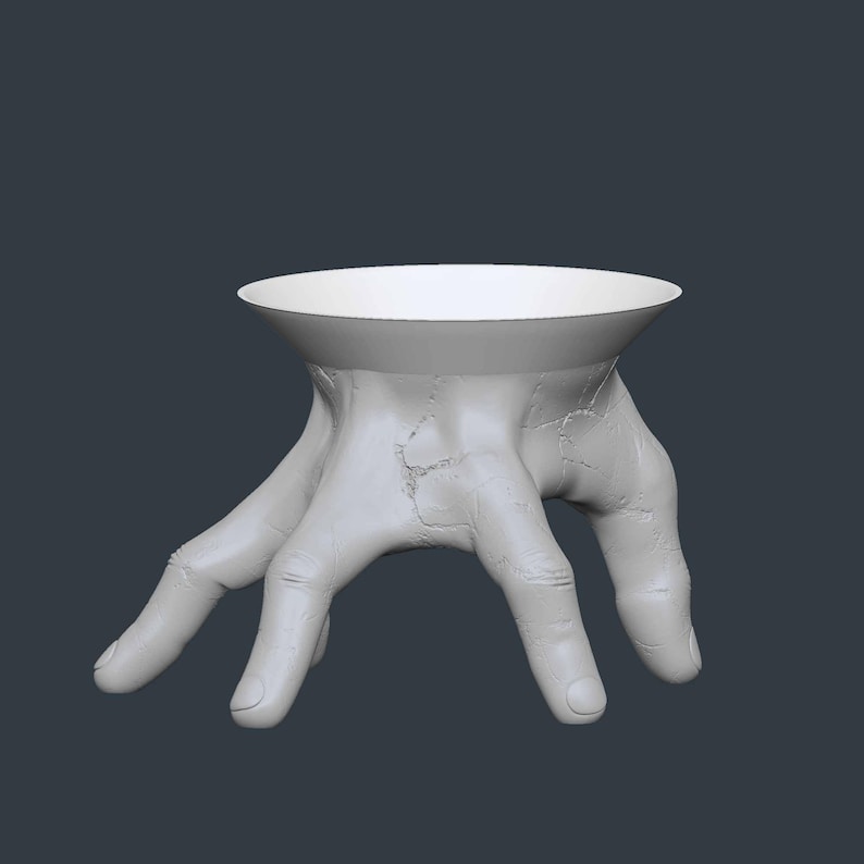 May include: A white, hand-shaped decorative bowl. The bowl's base is formed by a detailed, open hand with visible texture and cracks. The bowl itself is a smooth, circular indentation, creating a unique and artistic design.