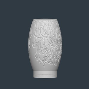 May include: A white, oval-shaped vase with an embossed floral design. The vase has a wide base and a slightly narrower top. The floral pattern covers the entire surface of the vase, creating a textured appearance.