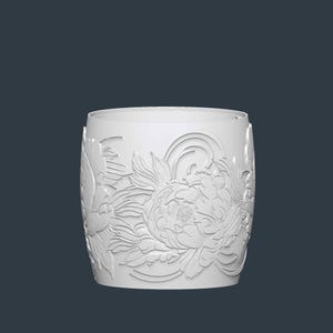 May include: A white cylindrical container with a floral relief design. The detailed carving features large peony blooms and stylized leaves. The container has a smooth, unadorned rim and a solid base, set against a dark background.