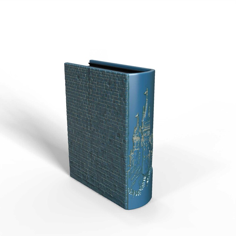 K&ouml;nnte beinhalten: Eine blaue, dekorative, buchf&ouml;rmige Box mit einem Ziegelmuster auf der Vorderseite und einem Schlossdesign auf dem Buchr&uuml;cken. Die Box steht aufrecht vor einem wei&szlig;en Hintergrund.
