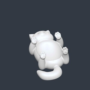 May include: A white, stylized cat figurine lying on its back with its paws in the air. The cat has a rounded body, a tail, and detailed paw pads. The figurine is set against a dark gray background.