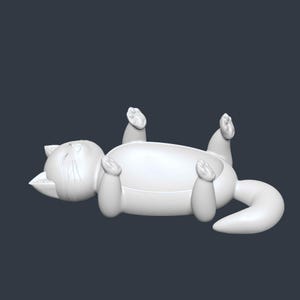 May include: A white, stylized cat figurine lying on its back with its paws in the air. The cat has a rounded body, a curled tail, and a smiling expression. The figurine is a solid color and appears to be made of plastic or ceramic.