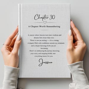 May include: A white book with the text "Chapter 30" and "A Chapter Worth Remembering." The book's pages contain inspirational text, and the name "Jessica" is at the bottom. The book is held by two hands.