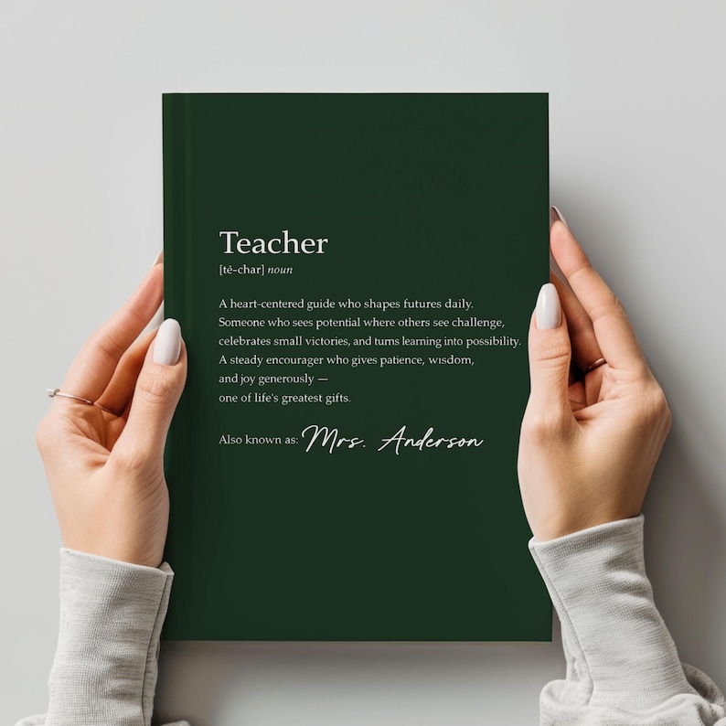 May include: A dark green notebook with the definition of "Teacher" printed in white. The definition includes the text "A heart-centered guide who shapes futures daily." The notebook is personalized with the name "Mrs. Anderson".